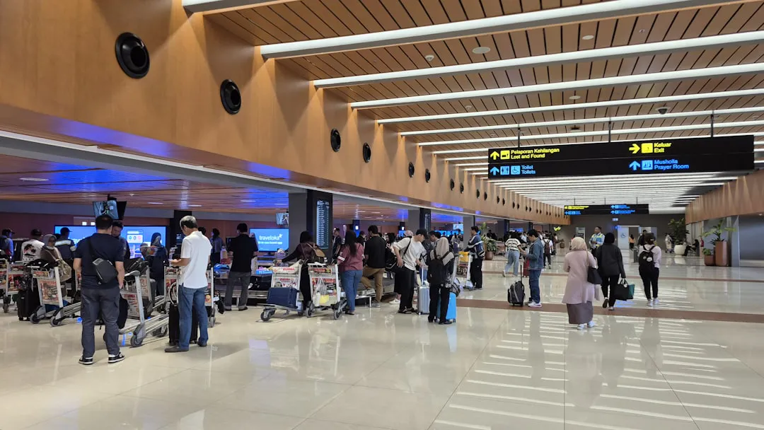 Melhor transfer em Nova York com motorista brasileiro 3 People walking through a modern airport terminal with luggage.